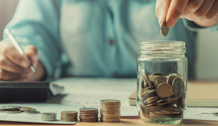 Change jar filled with coins and another coin being dropped in