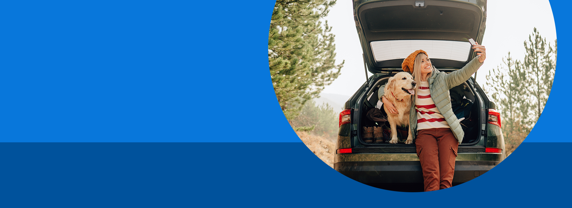 Woman taking a selfie with her dog in the trunk of a car on a blue background.