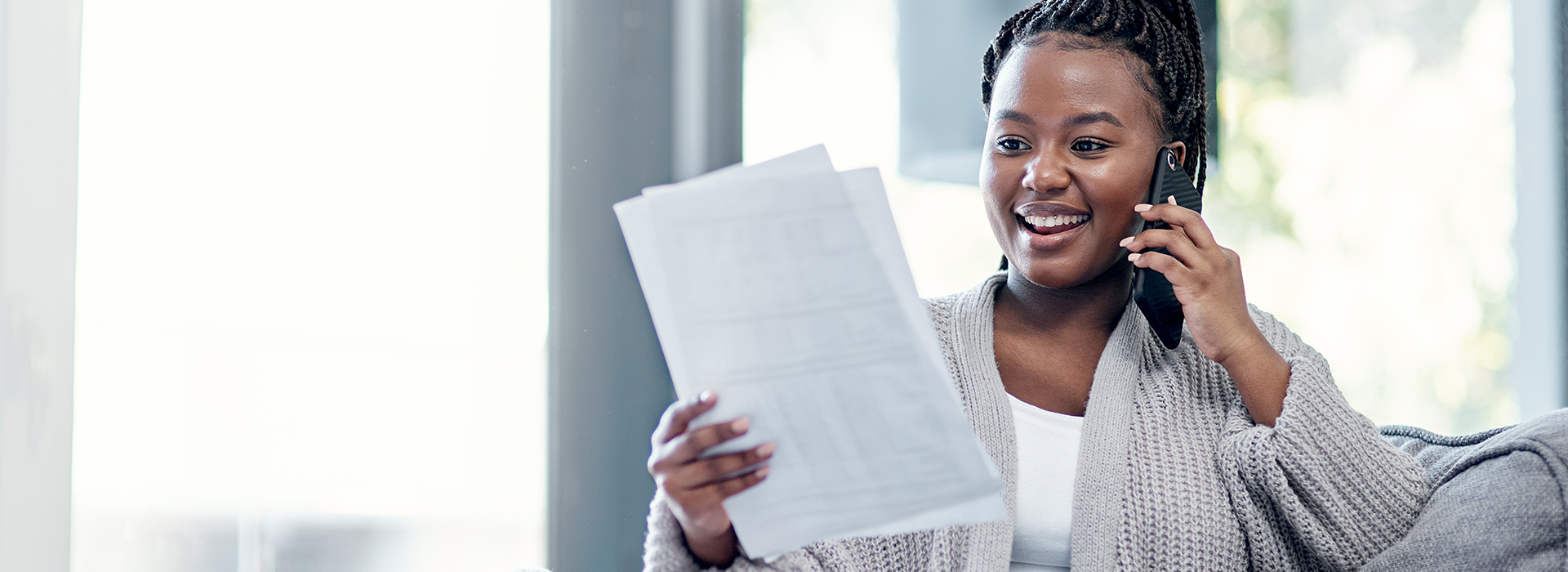 Woman speaking on cell phone while looking at sheets of paper.