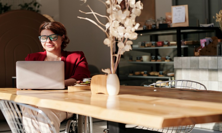 woman in wheelchair at coffee shop researching financial literacy