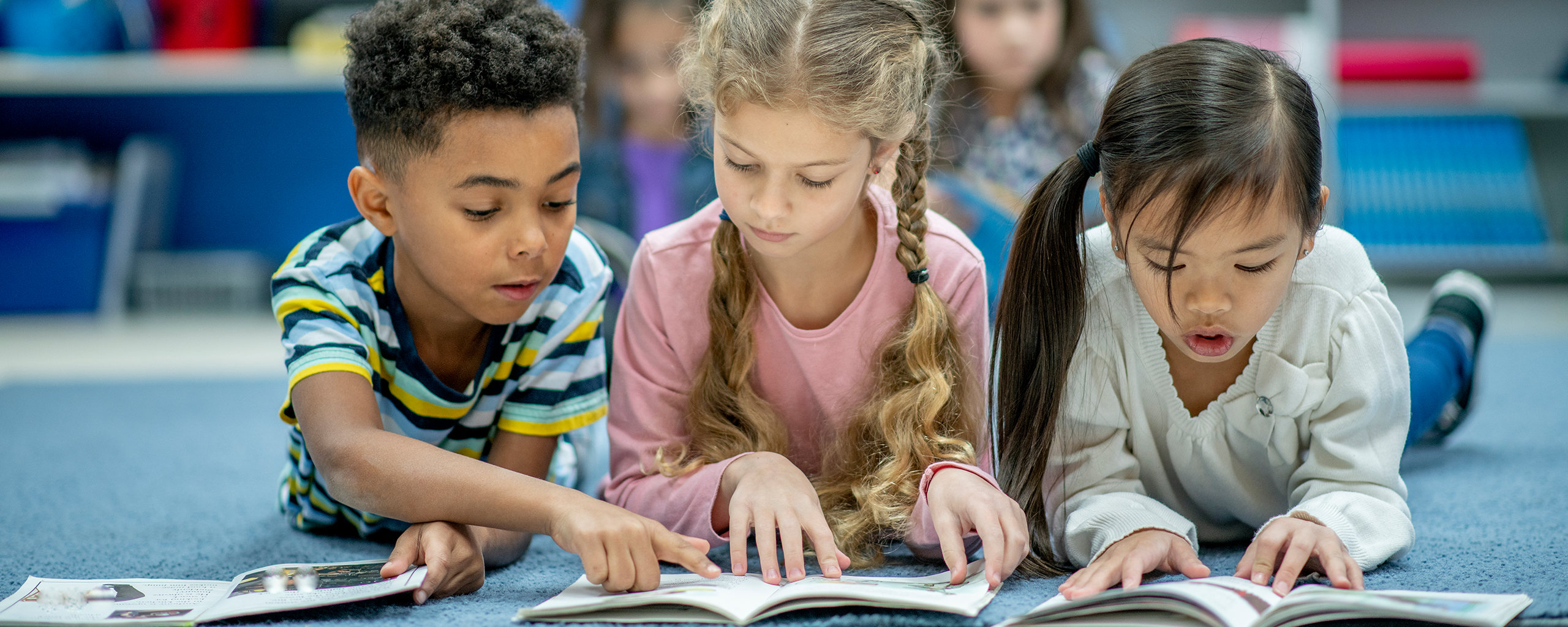 Diverse children reading books together on the floor.