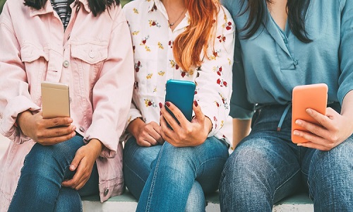 three women sitting down, texting on their cell phones