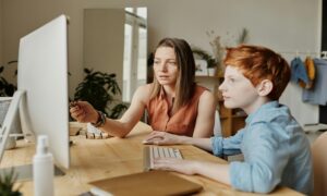 Mother teaching son about money using a computer.