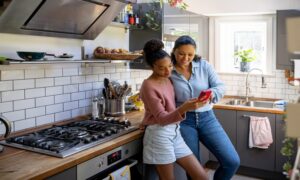 Happy mother and daughter looking at videos on social media together - family concepts