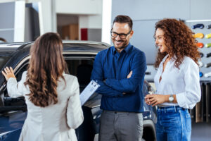 A car salesman is showing new cars to a couple. Car sales