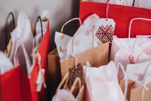 Red and brown holiday gift bags with tissue paper.