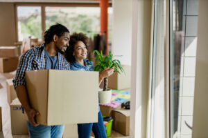 Young happy couple moving into new home while holding boxes