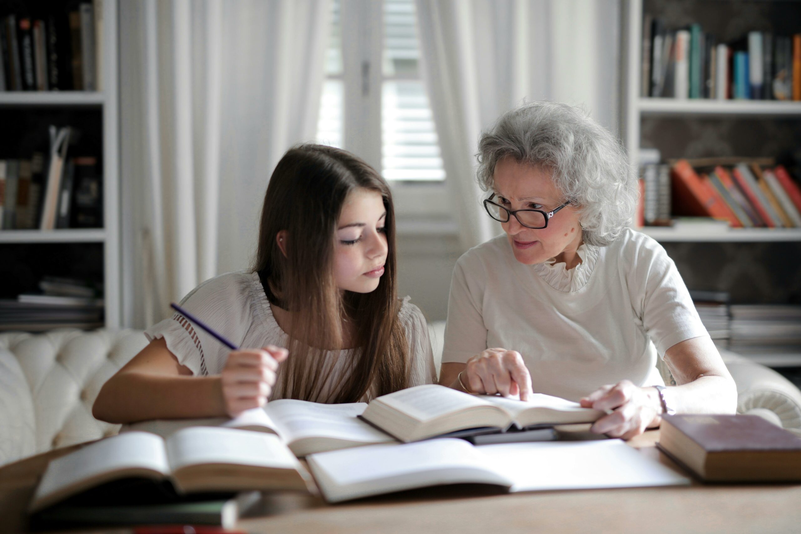 Grandma teaching her younger grand-daughter about finances by pointing to a book.