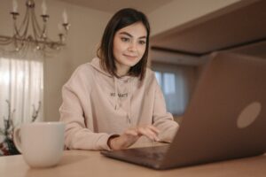Young girl typing on computer wearing a you matter beige sweatshirt
