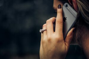 Woman holding iphone to ear listening with diamond ring on.